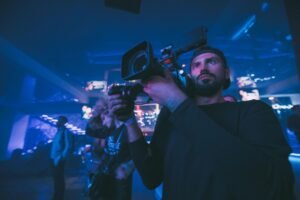 Camera operator filming under blue stage light