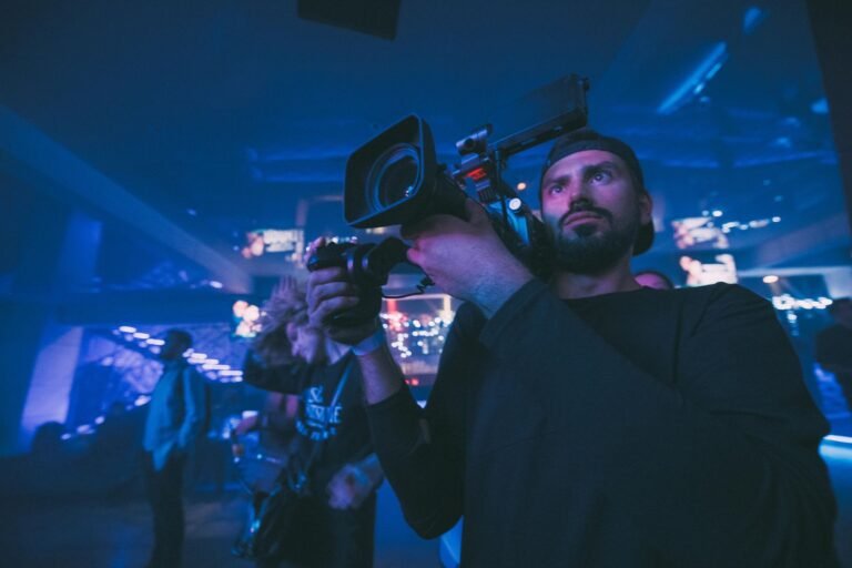 Camera operator filming under blue stage light