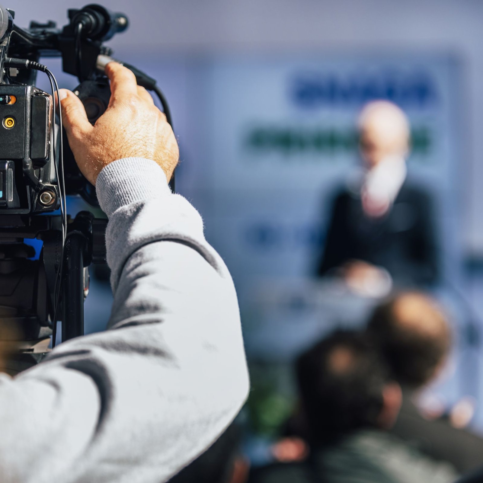 Shoulder camera filming a speaker at a podium