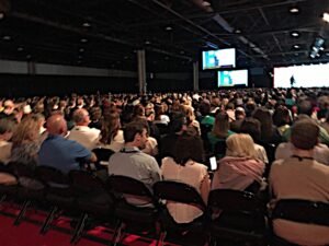 Large conference audience facing the stage screens