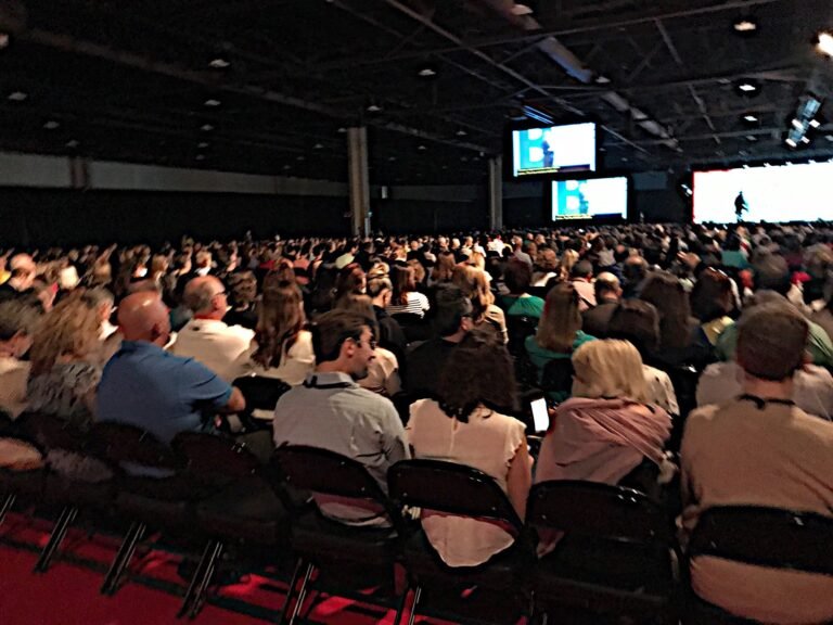 Large conference audience facing the stage screens