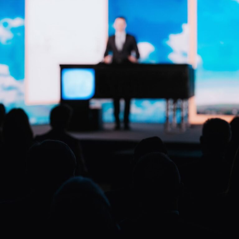 Speaker at a podium with the audience in silhouette